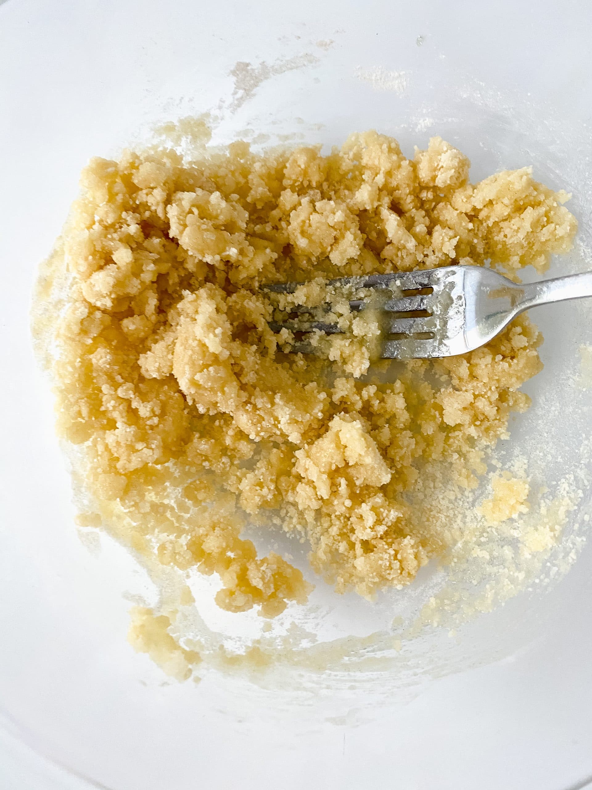 crumble coating mixture with a silver fork in a glass mixing bowl