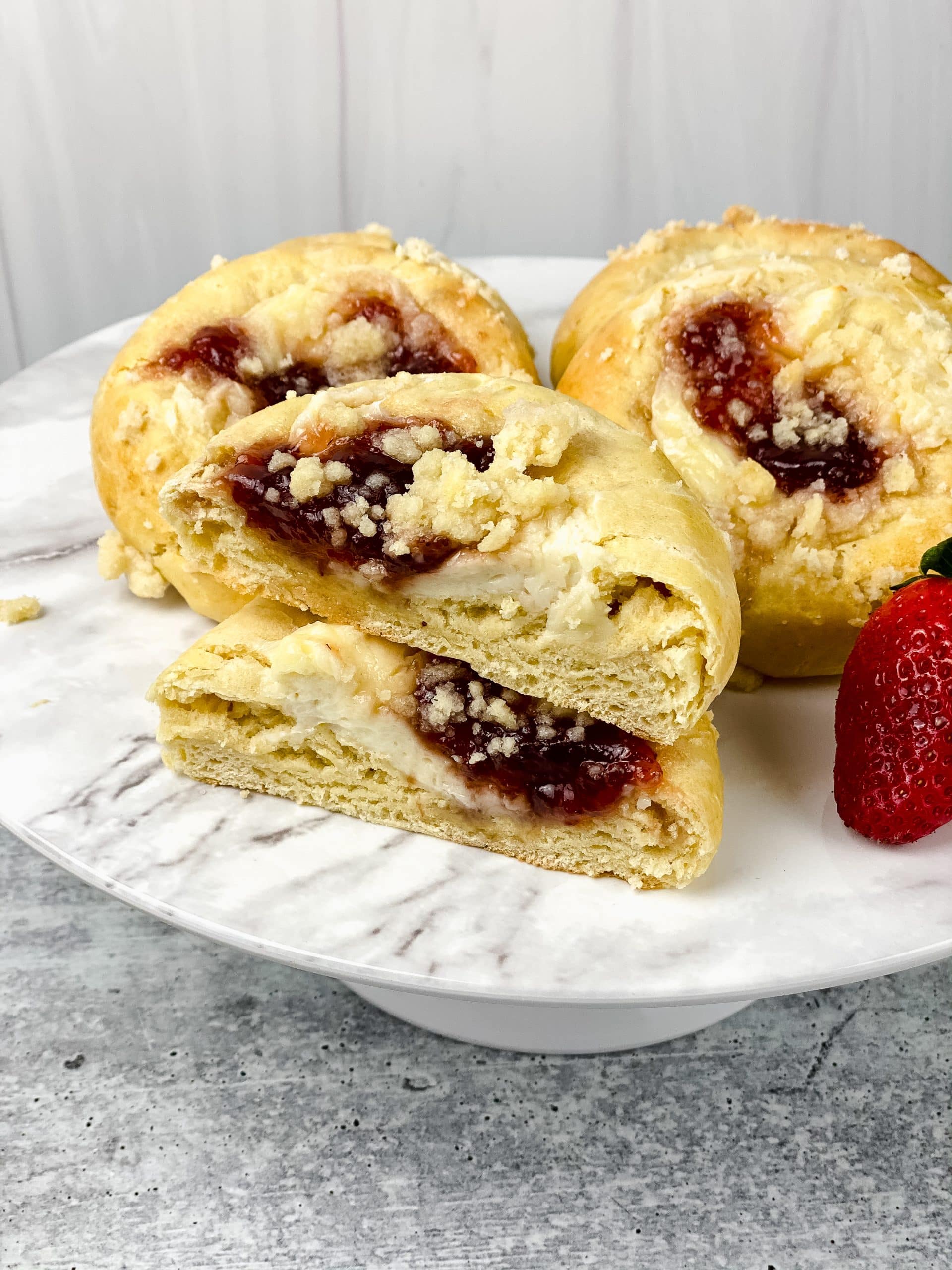 sliced homemade strawberry cream cheese danish on a white serving platter
