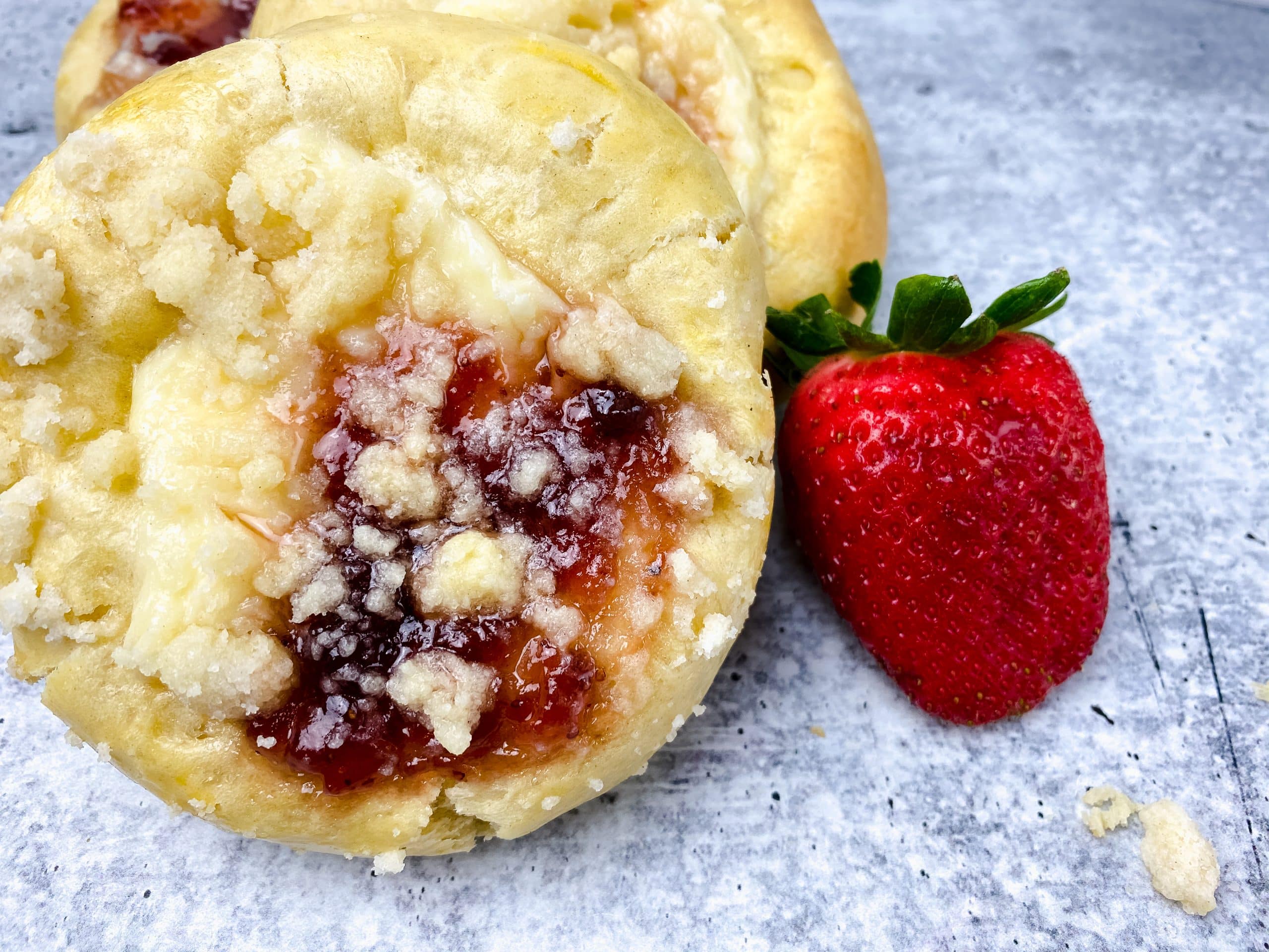 two homemade strawberry cream cheese danish next to fresh berries