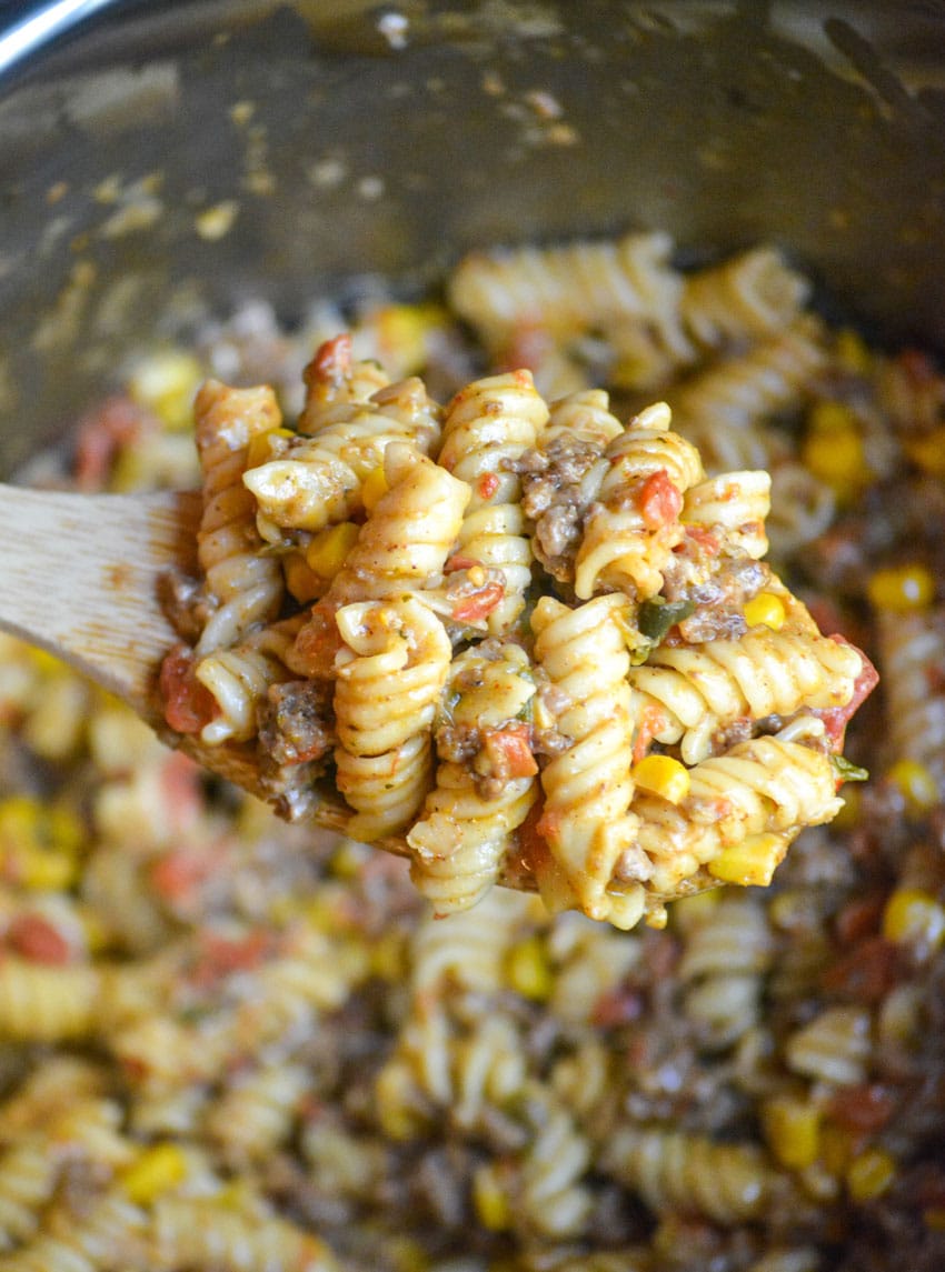 a wooden spoon holding up a scoop of instant pot taco pasta