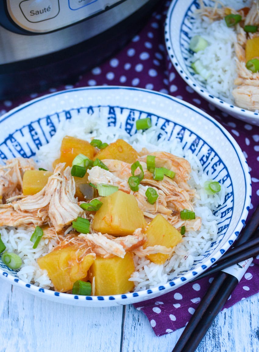 two bowls of instant pot pineapple chicken next to a pressure cooker