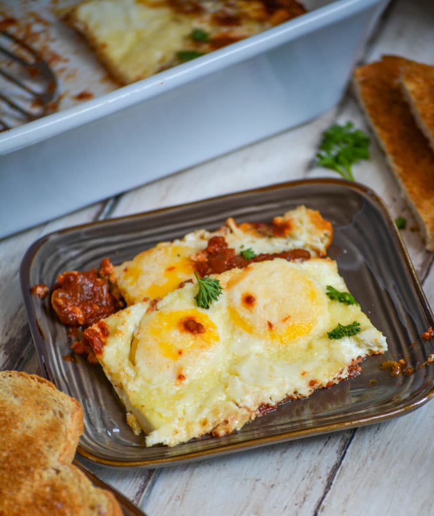 baked eggs in purgatory with tomato sauce on a brown plate with toast on the side