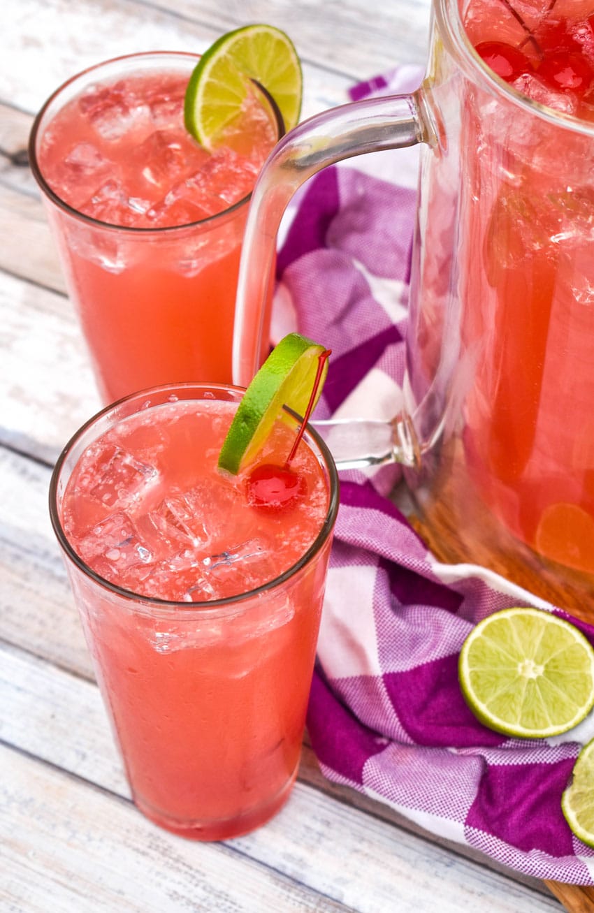 two glasses of cherry limeade on a wooden board