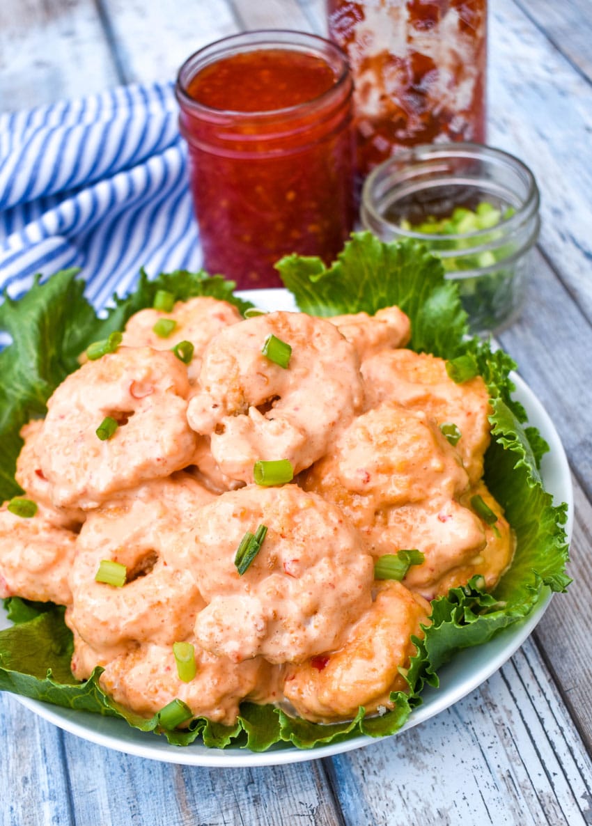 crispy air fryer bang bang shrimp in a lettuce leaf lined white bowl