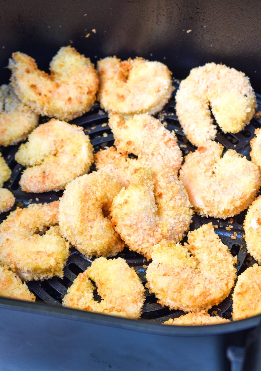 crispy panko coated shrimp in the basket of an air fryer