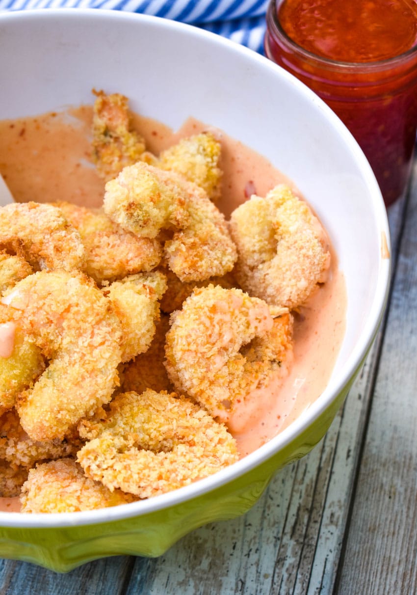 crispy air fryer shrimp in a large mixing bowl filled with bang bang sauce