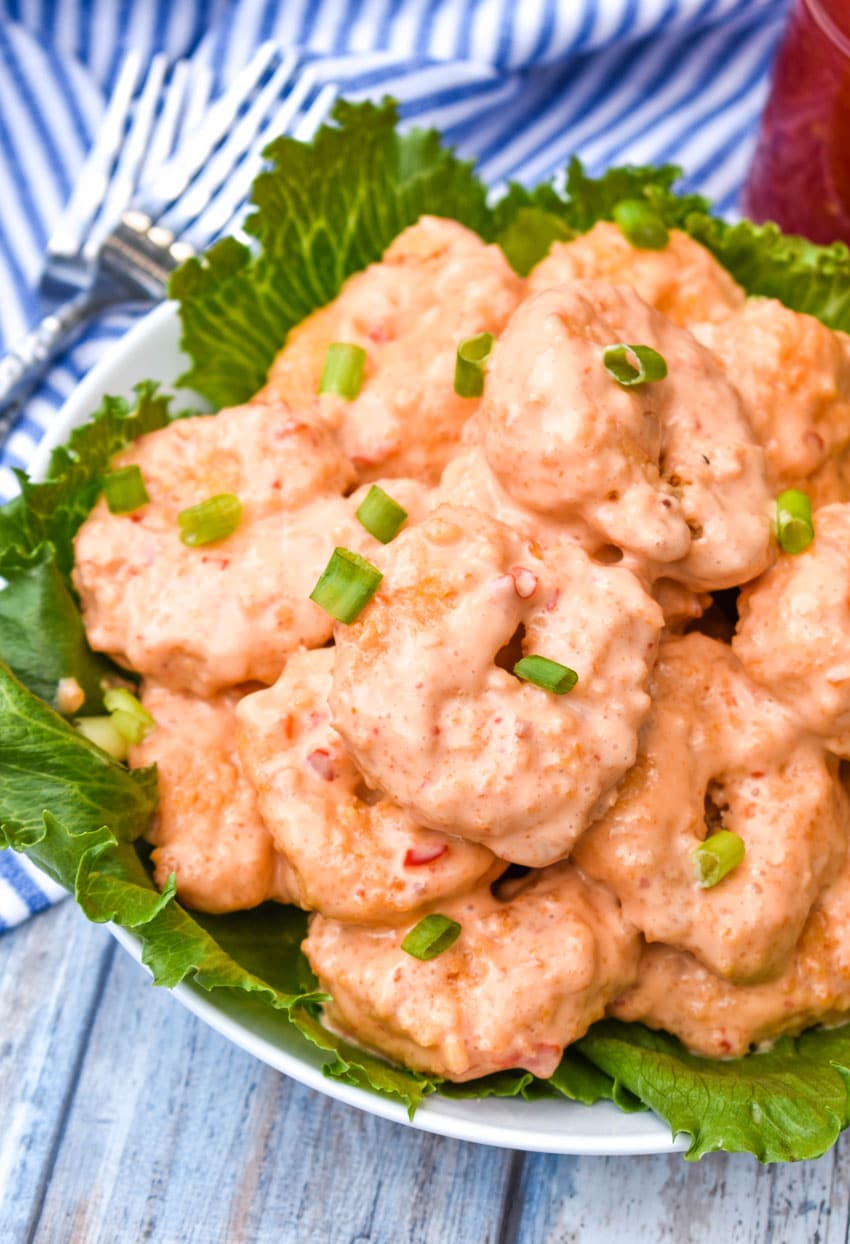 crispy air fryer bang bang shrimp in a lettuce leaf lined white bowl