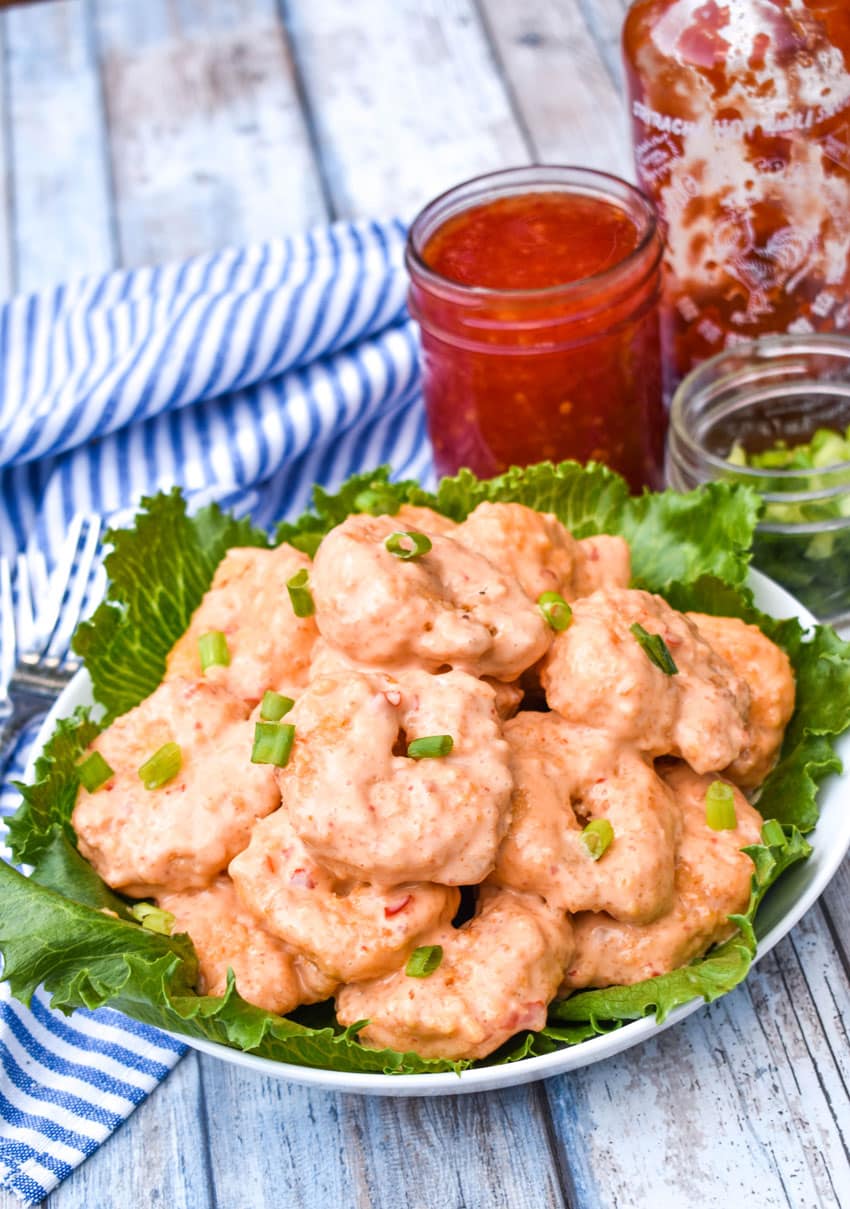 crispy air fryer bang bang shrimp in a lettuce leaf lined white bowl