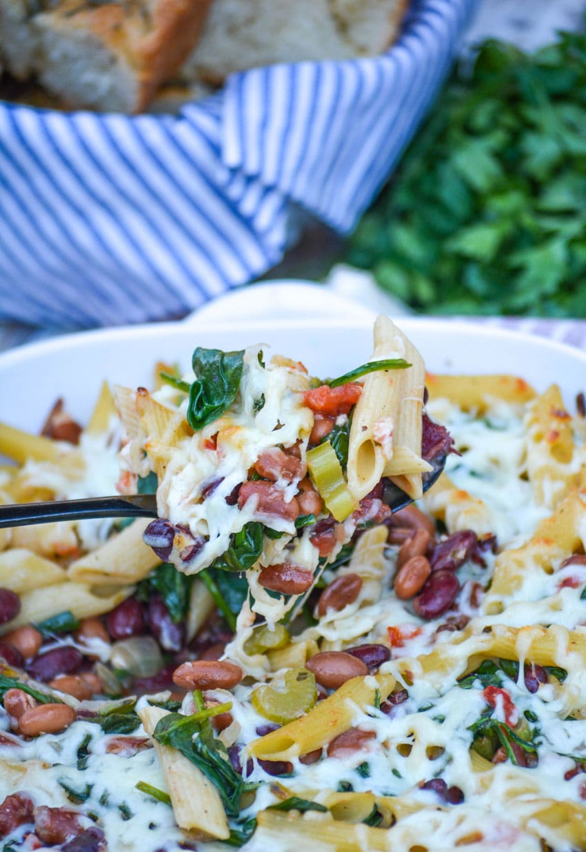 a serving spoon holding up a scoop of baked pasta e fagioli