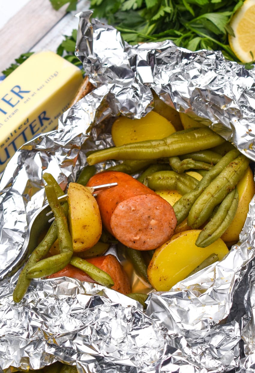 opened oven baked cajun foil packets on a rimmed baking sheet