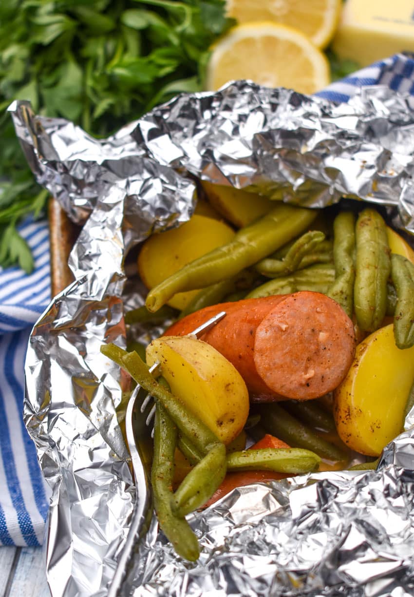 opened oven baked cajun foil packets on a rimmed baking sheet