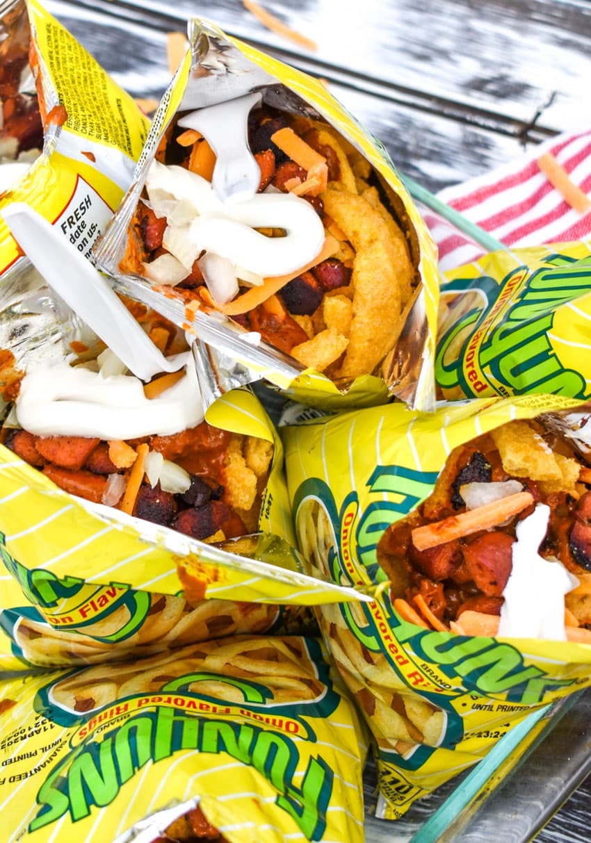 walking chili dogs arranged in a glass dish with white plastic forks stuck in them