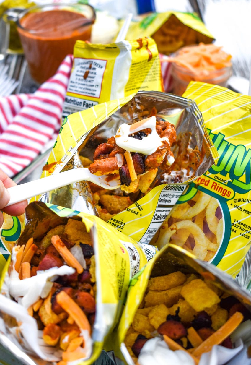a plastic fork lifting a scoop of walking chili cheese dog out of a funyon bag