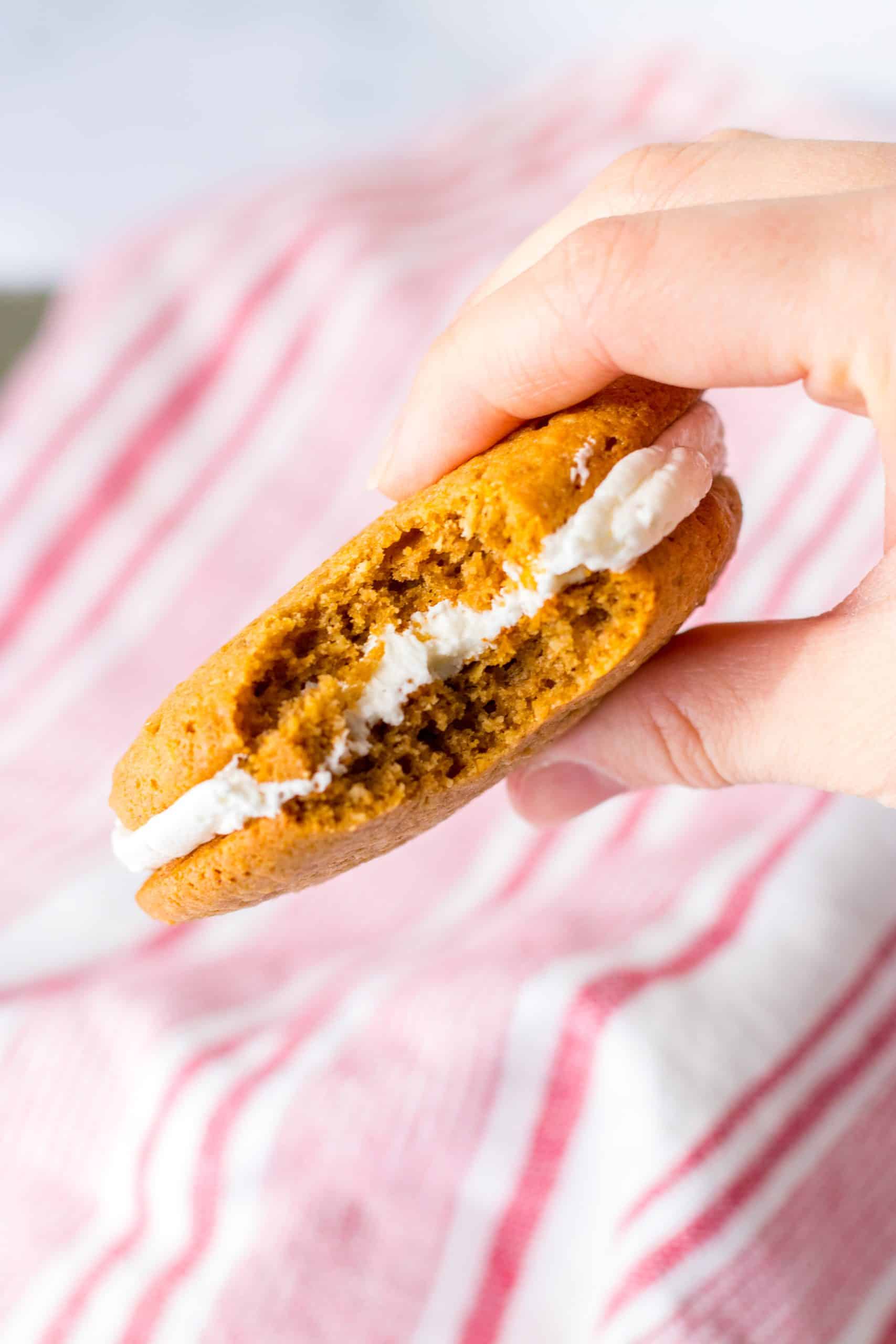 a hand holding up a bitten homemade oatmeal cream pie