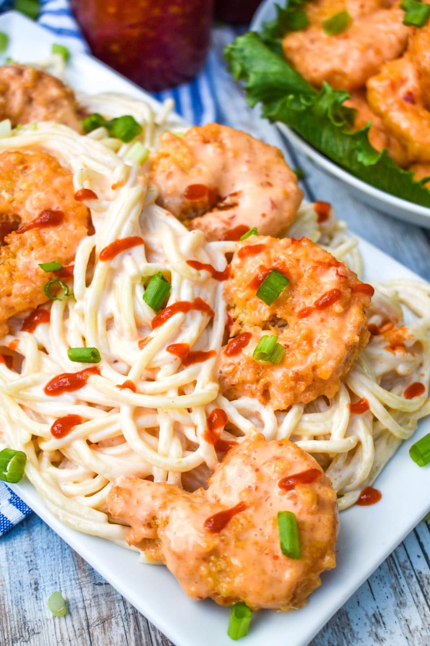 creamy bang bang shrimp pasta on a white serving platter