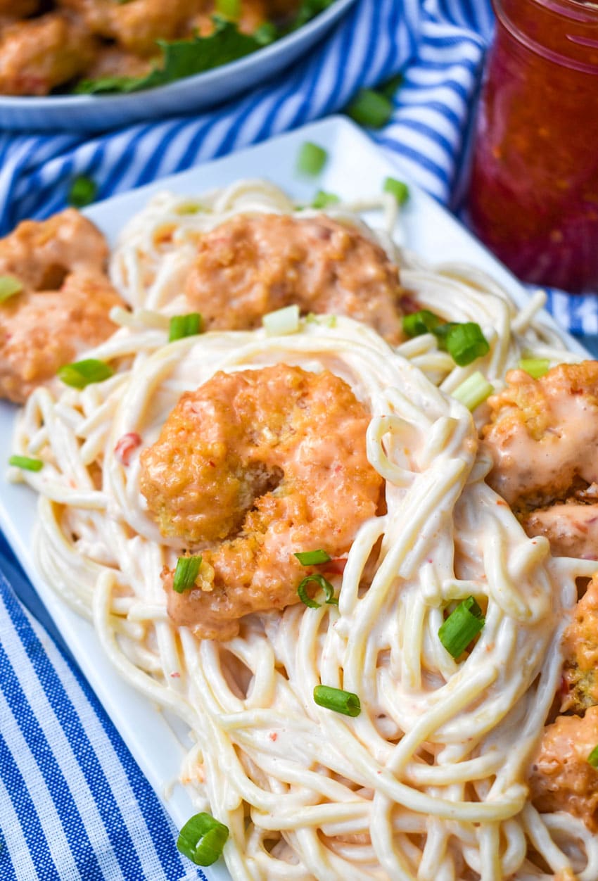 bangbang shrimp pasta on a white serving platter topped with thinly sliced green onions