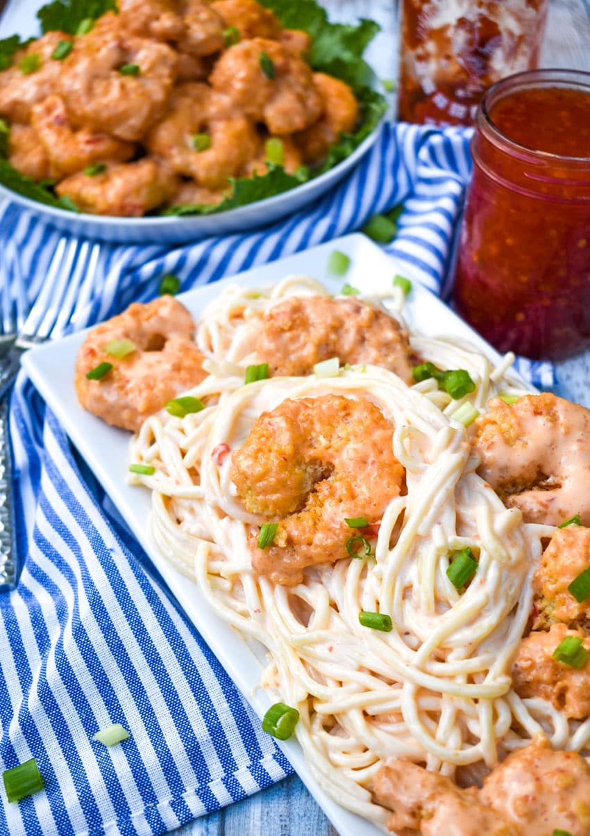 bangbang shrimp pasta on a white serving platter topped with thinly sliced green onions