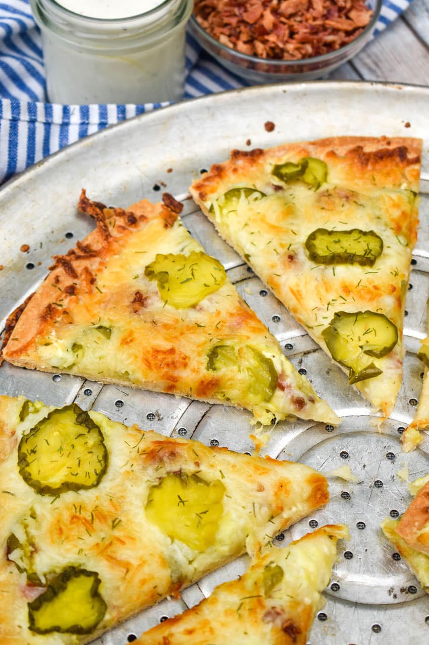 slices of dill pickle pizza on a perforated pizza pan
