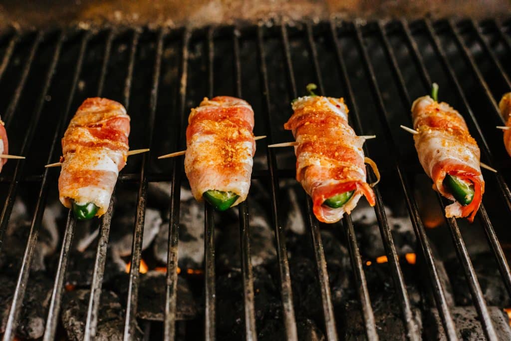 bacon wrapped jalapeno poppers on a hot grill wrack