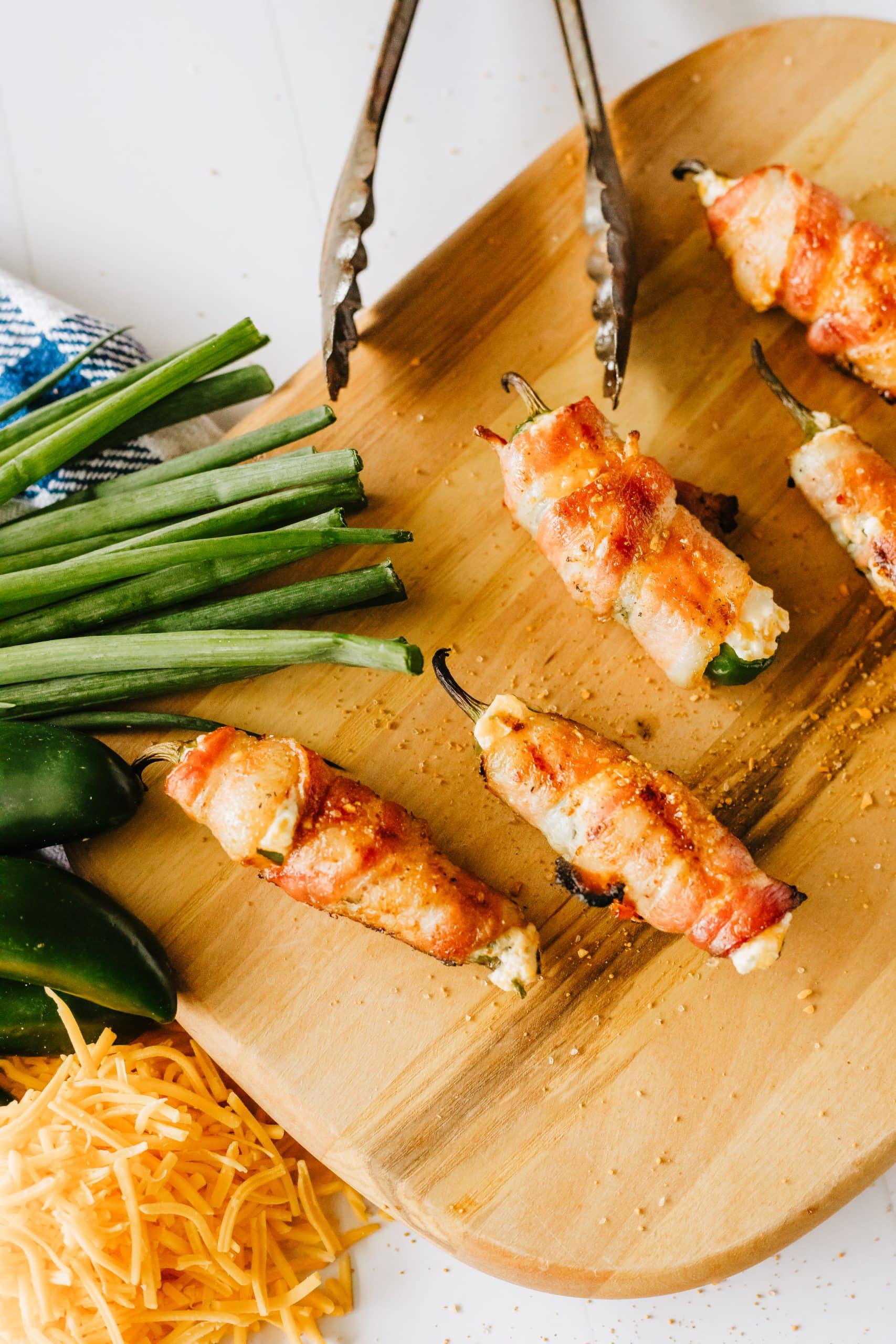 bacon wrapped grilled jalapeno poppers on a wooden cutting board
