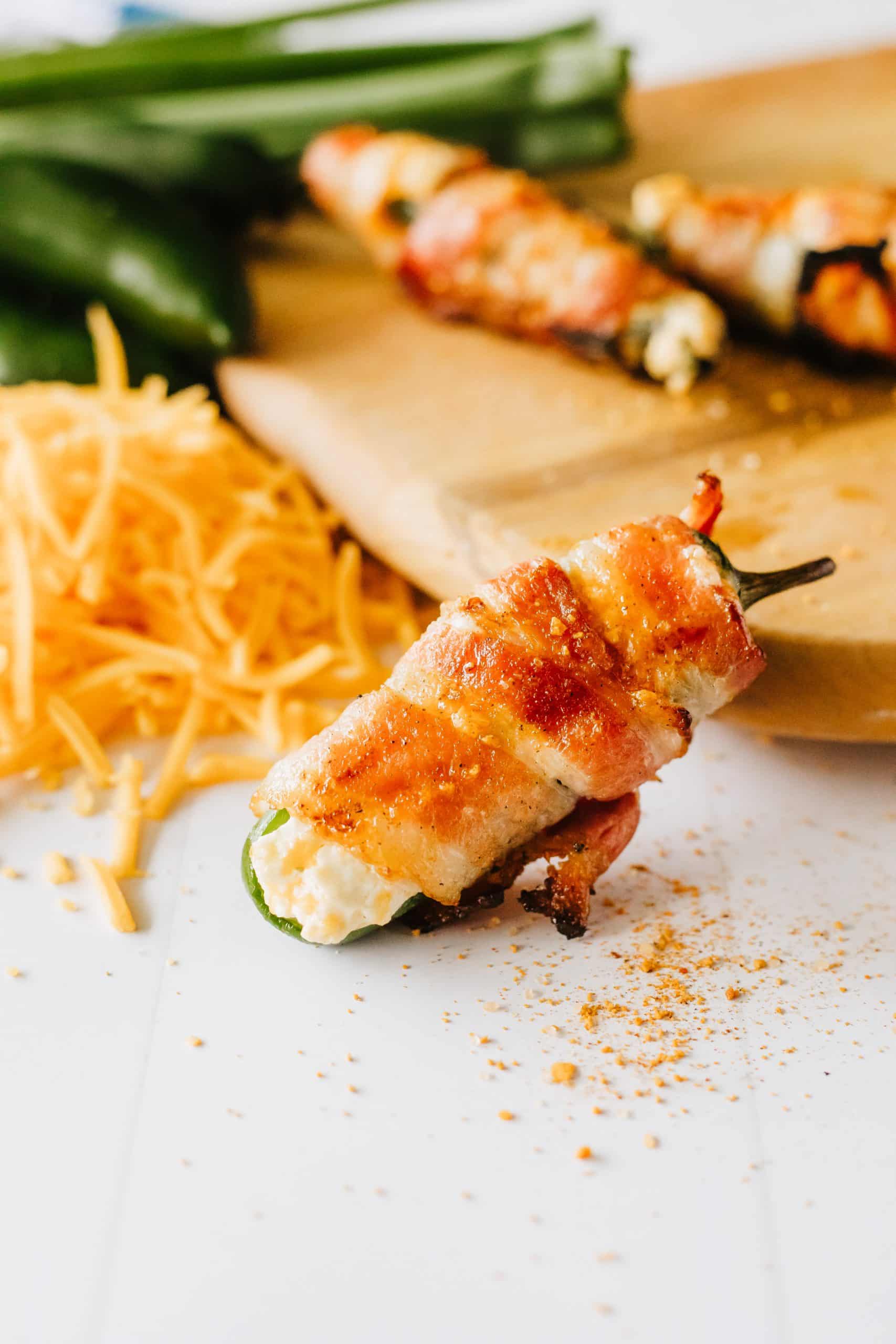 a grilled jalapeno popper with bacon resting on a wooden cutting board