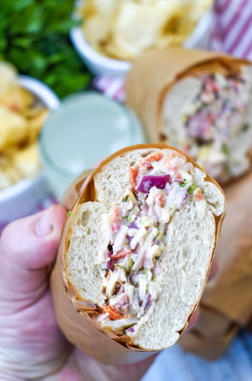 a hand holding up half of an italian deli chop chop sub sandwich