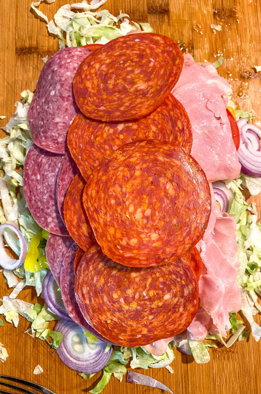ingredients to make a tiktok chopped italian sandwich on a wooden cutting board