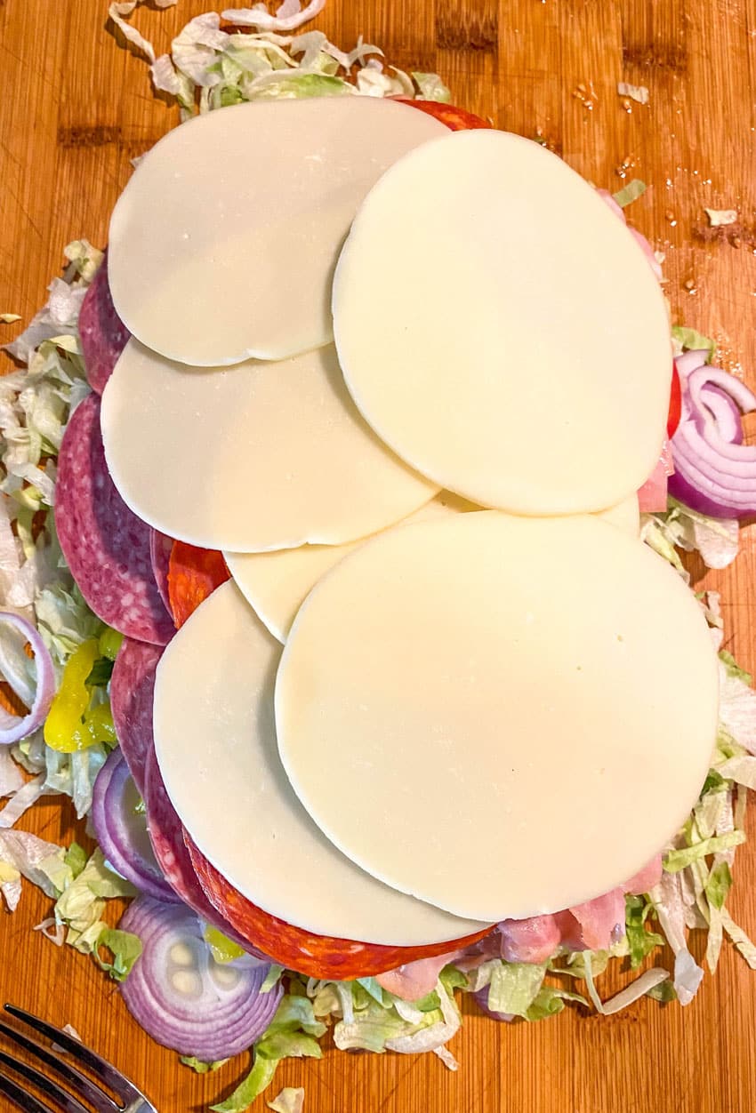 ingredients to make a tiktok chopped italian sandwich on a wooden cutting board