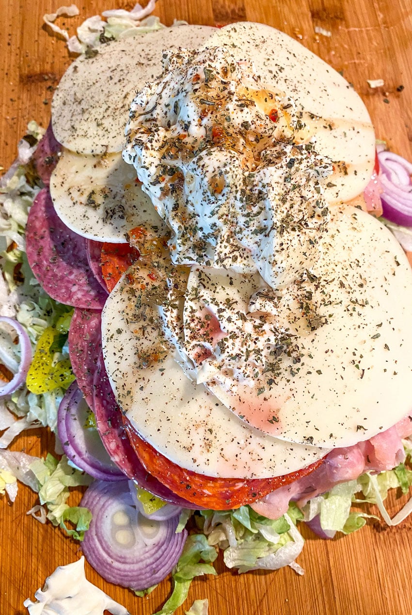 ingredients to make a tiktok chopped italian sandwich on a wooden cutting board