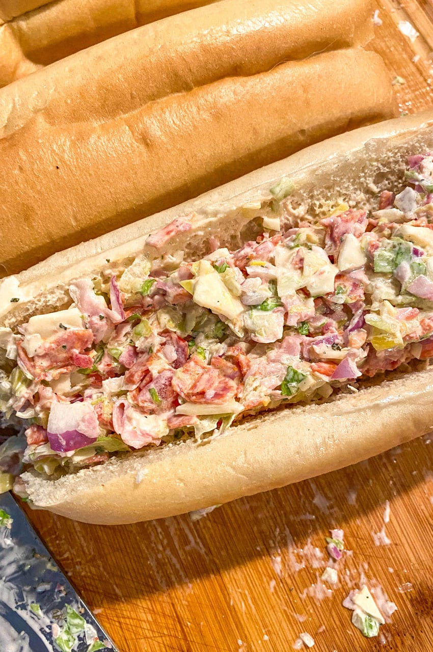 a stuffed chopped italian sub sandwich on a wooden cutting board