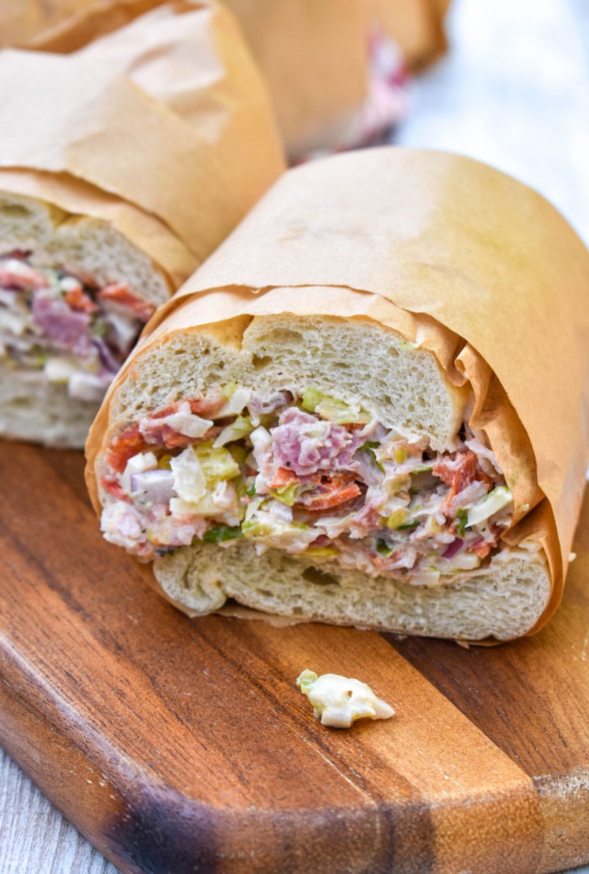 two halves of an italian deli chop chop sandwiches on a wooden cutting board