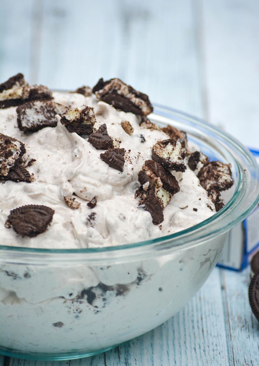 oreo fluff salad topped with crushed sandwich cookies in a large glass bowl
