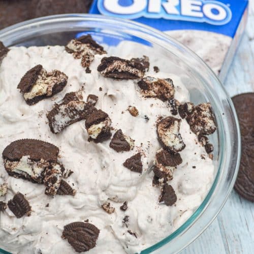 oreo fluff salad in a glass mixing bowl surrounded by oreo sandwich cookies