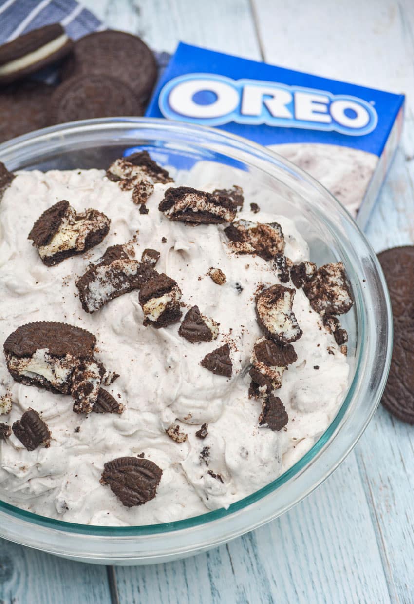 oreo fluff salad in a glass mixing bowl surrounded by oreo sandwich cookies