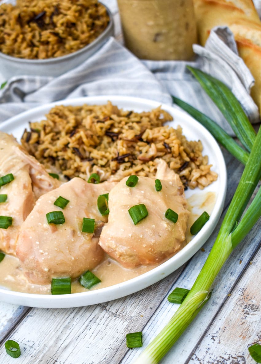 slow cooker sour cream and onion chicken topped with green onions and potato chips on a white plate with rice on the side