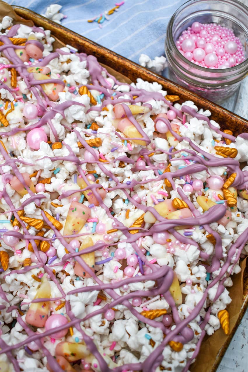unicorn munch popcorn mix on a parchment paper lined baking sheet