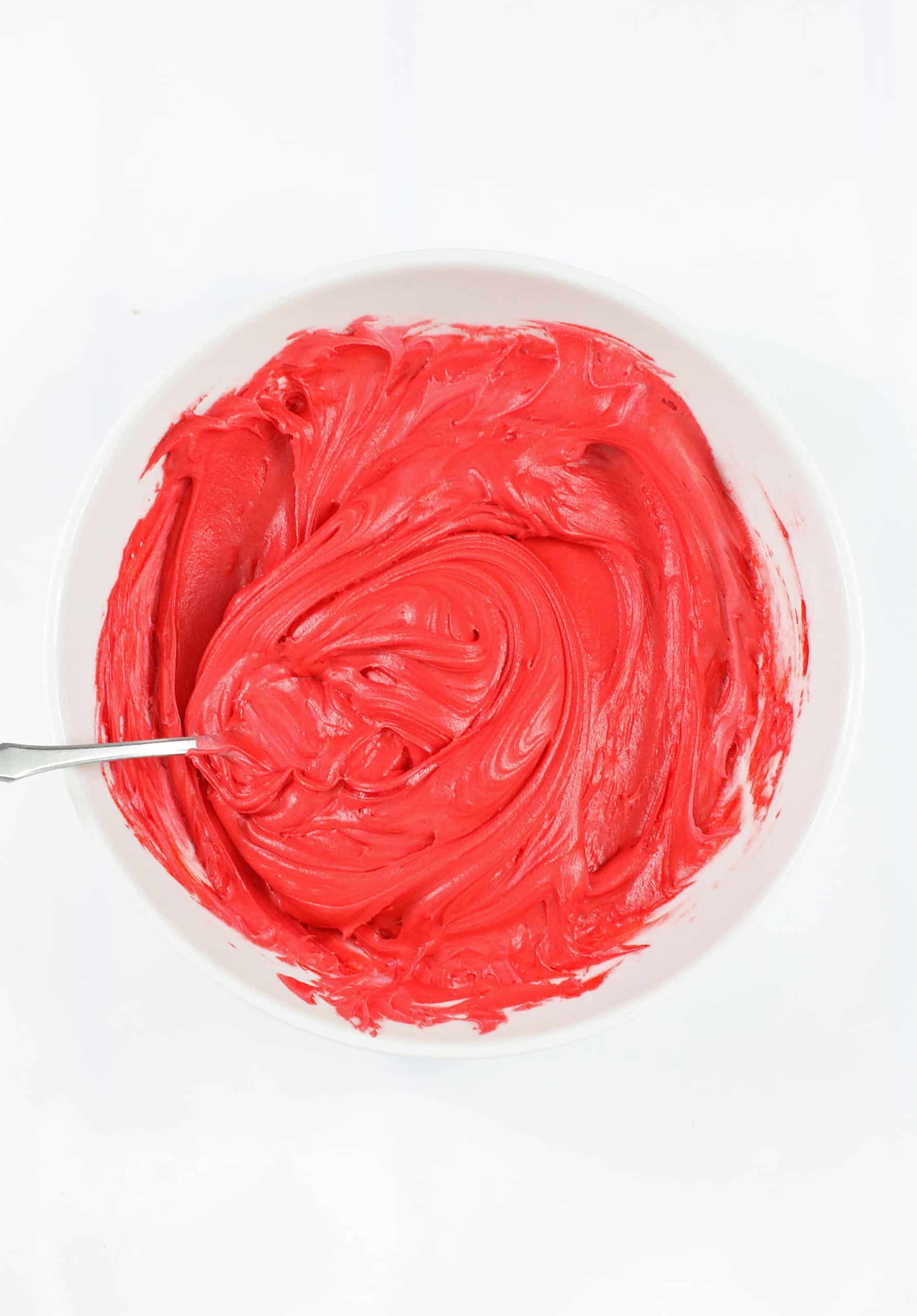 red frosting in a small glass bowl