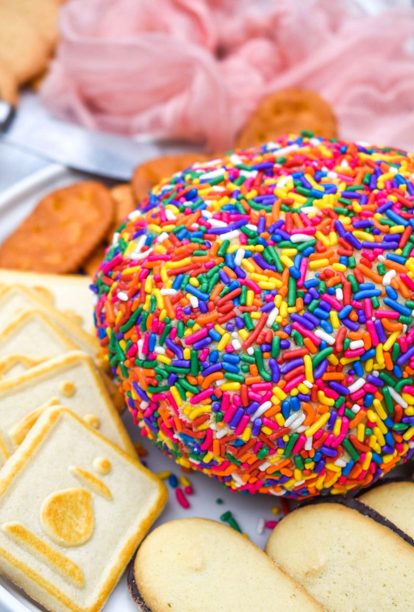 a cake batter cheese ball on a white plate surrounded by assorted cookies