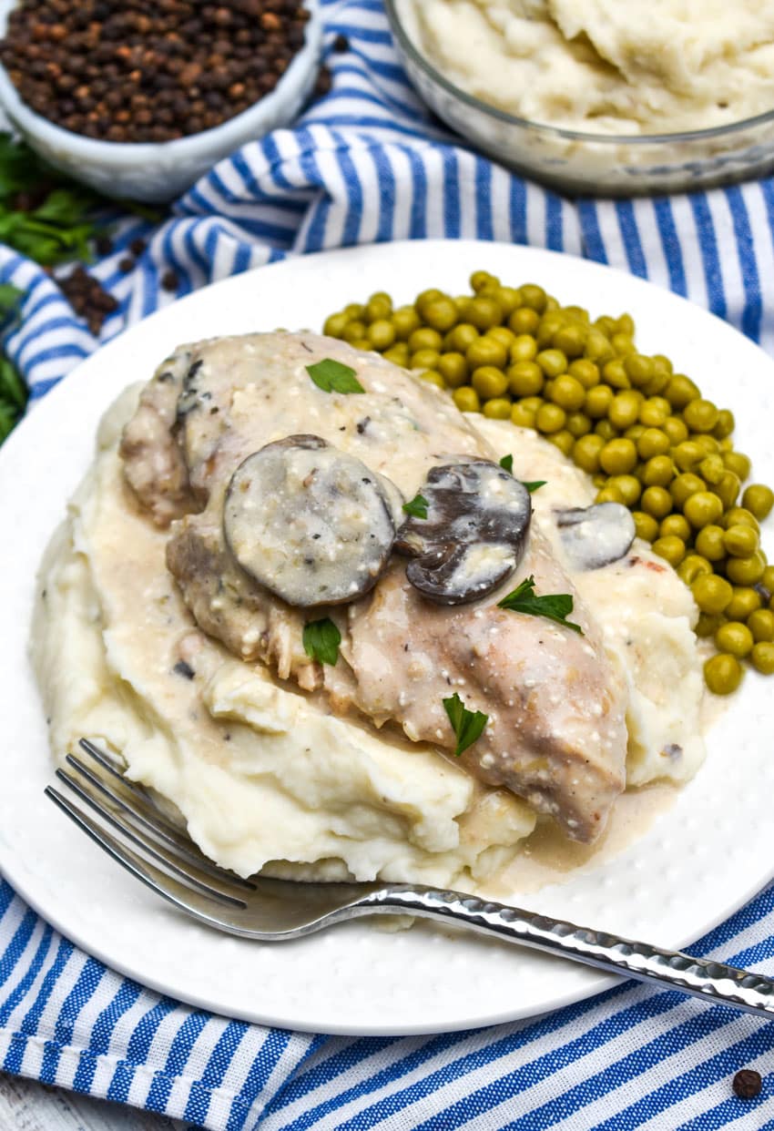 Slow Cooker Peppercorn Chicken with Mushrooms over mashed potatoes on a white plate