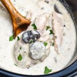 a wooden spoon in a black crock filled with Slow Cooker Peppercorn Chicken with Mushrooms