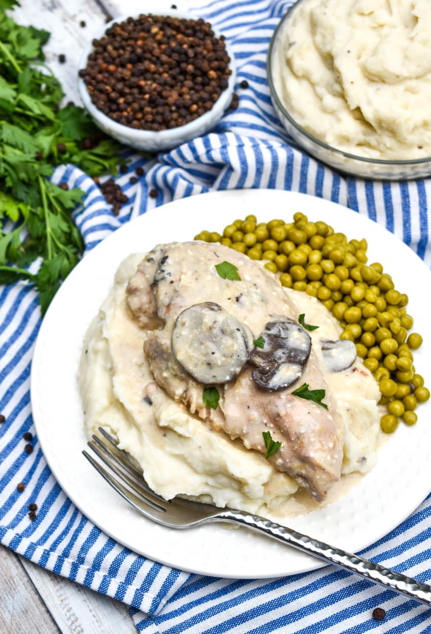 crockpot parmesan peppercorn chicken over mashed potatoes on a white plate
