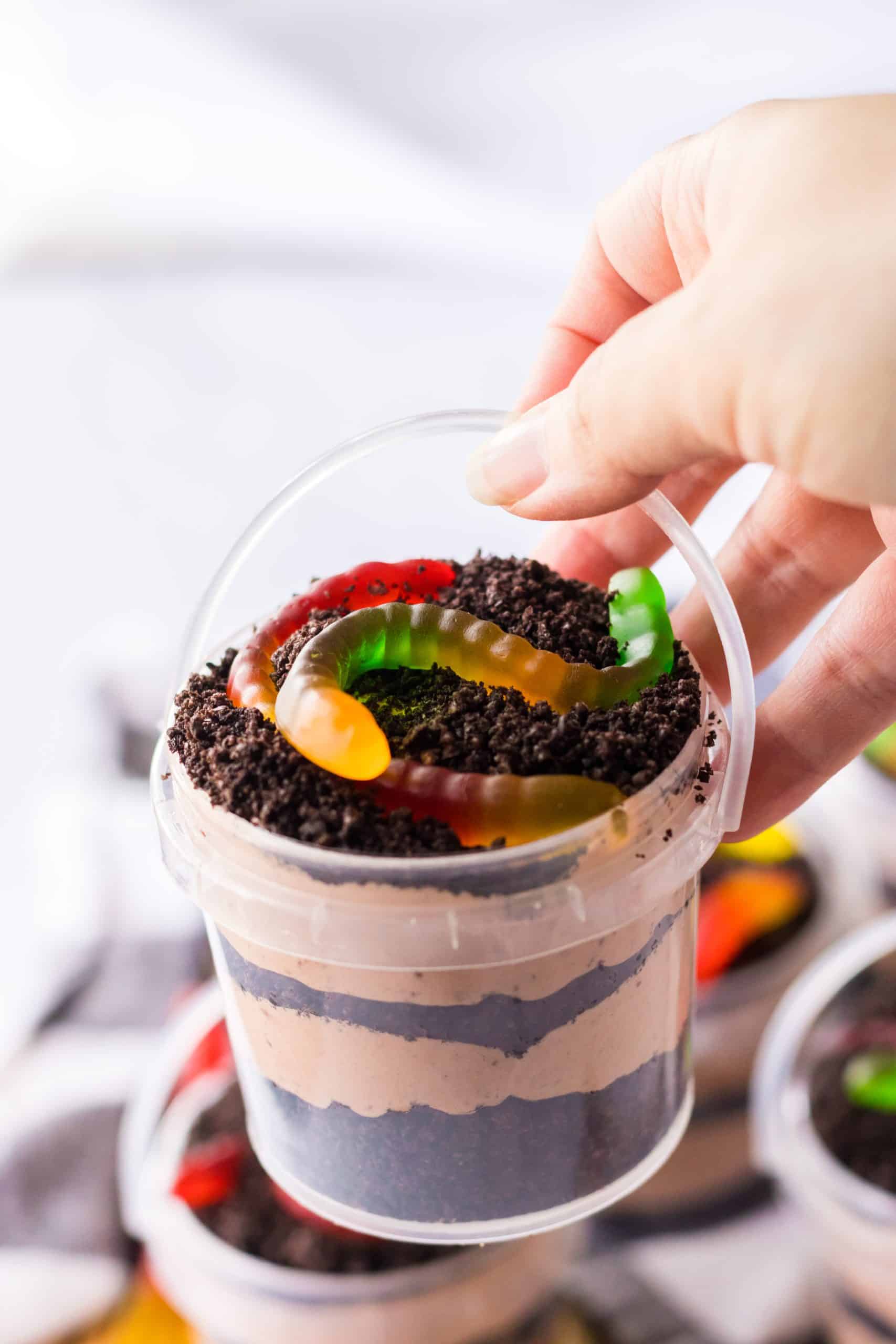 a hand holding up a small bucket of dirt pudding recipe