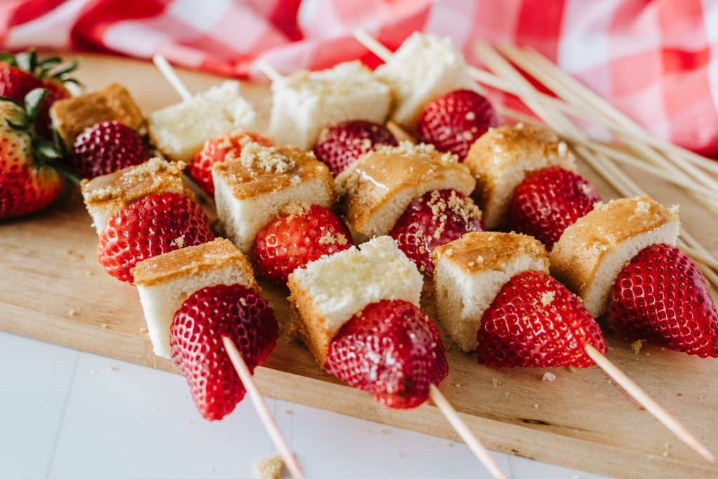 strawberry shortcake kabobs on a wooden cutting board