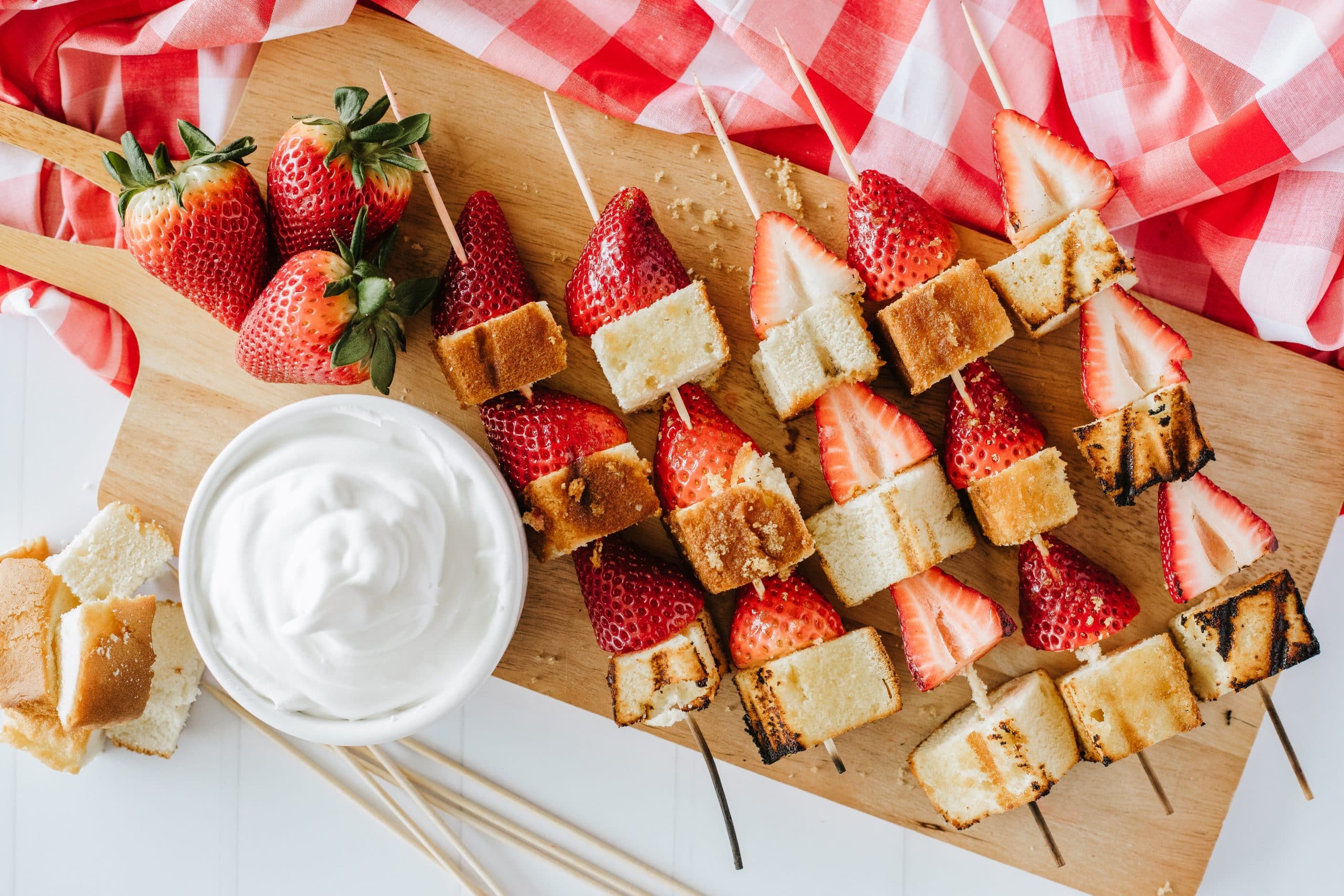 grilled strawberry dessert kabobs on a wooden cutting board