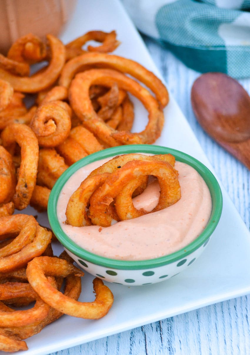 curly fries stuck in a small green bowl of mississippi comeback sauce
