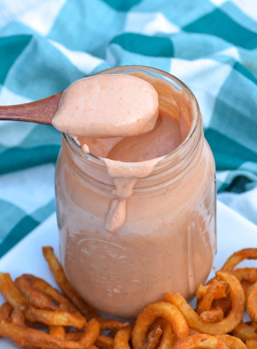 a spoon lifting a scoop of mississippi comeback sauce out of a glass mason jar