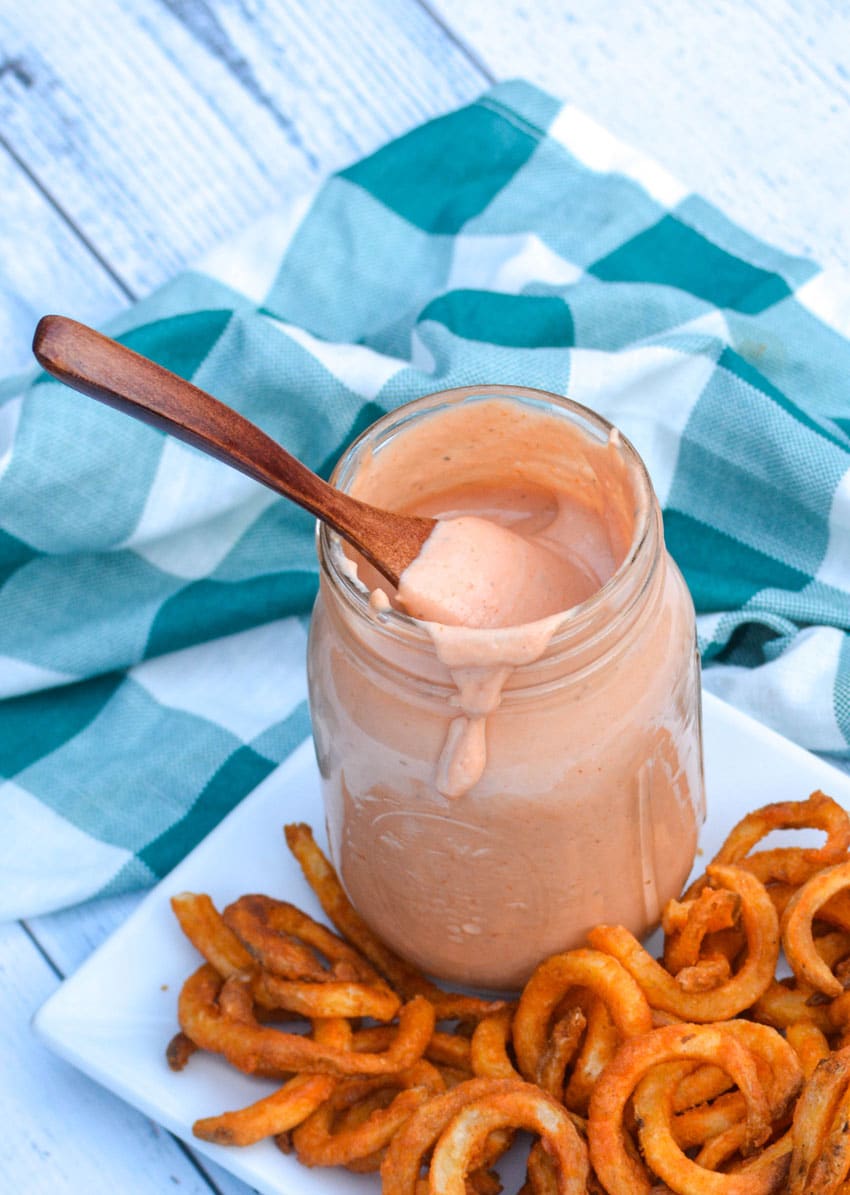 a wooden spoon in a glass jar filled with mississippi comeback sauce
