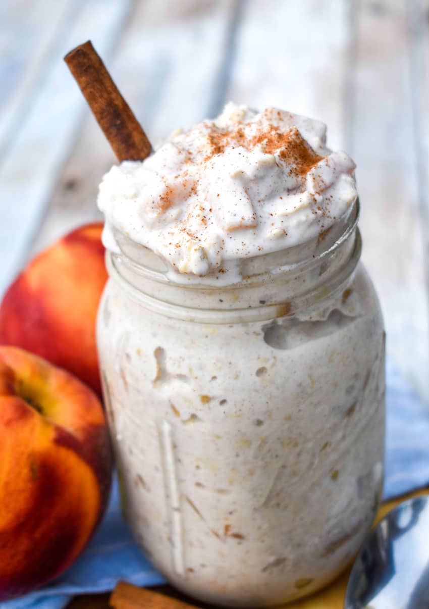 peaches and cream overnight oats in a glass mason jar topped with ground cinnamon and a cinnamon stick