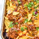 barbecue pulled pork nachos on a metal sheet pan