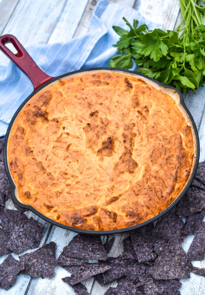 a red skillet filled with smoked buffalo chicken dip with chips on the side